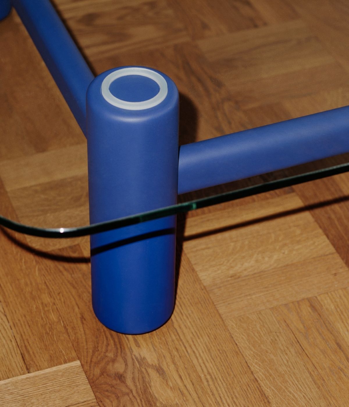
Detailaufnahme des Beins des Boundary Couchtisches in Blau von Massproductions, auf einem Holz-Boden. Das hochwertige Material des Beins und die präzise Verarbeitung kommen in dieser Nahaufnahme besonders zur Geltung, wobei der warme Holz-Boden eine harmonische Verbindung zum modernen Design des Tisches bildet.