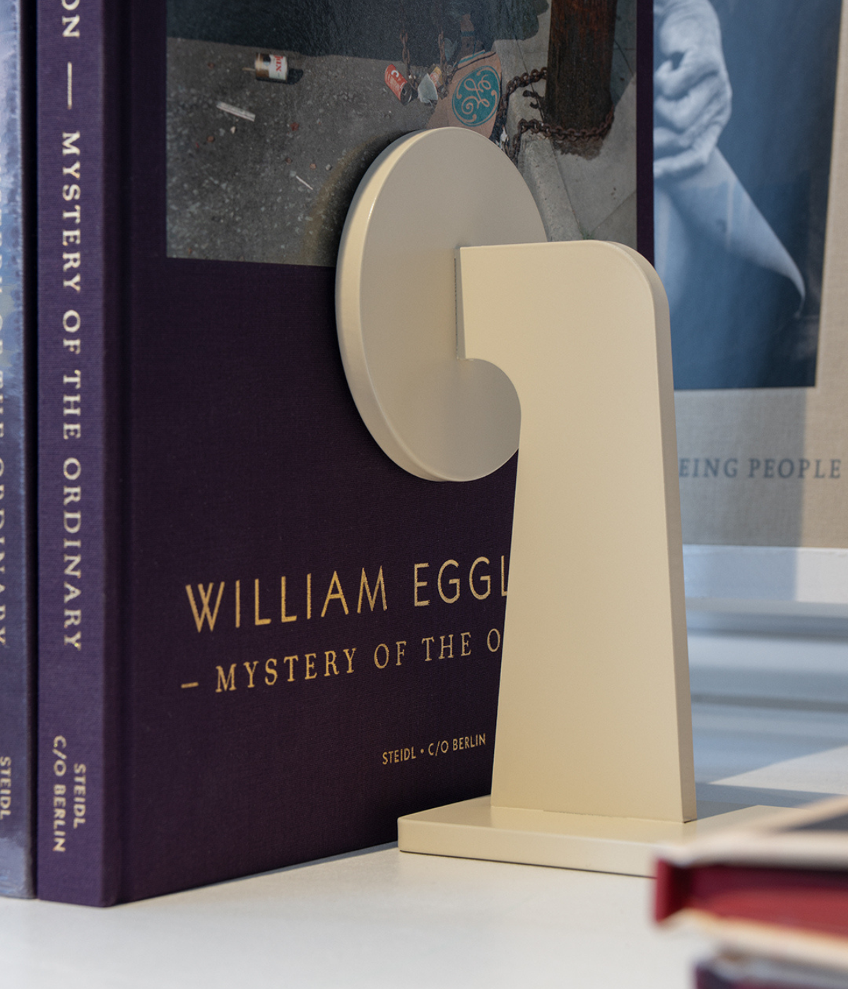 Massproductions BUFFER Buchstütze in reinem Weiß, aus pulverbeschichtetem Metall gefertigt und dekorativ mit aufgestellten Büchern inszeniert – minimalistisches, funktionales Accessoire für Regal oder Tisch
