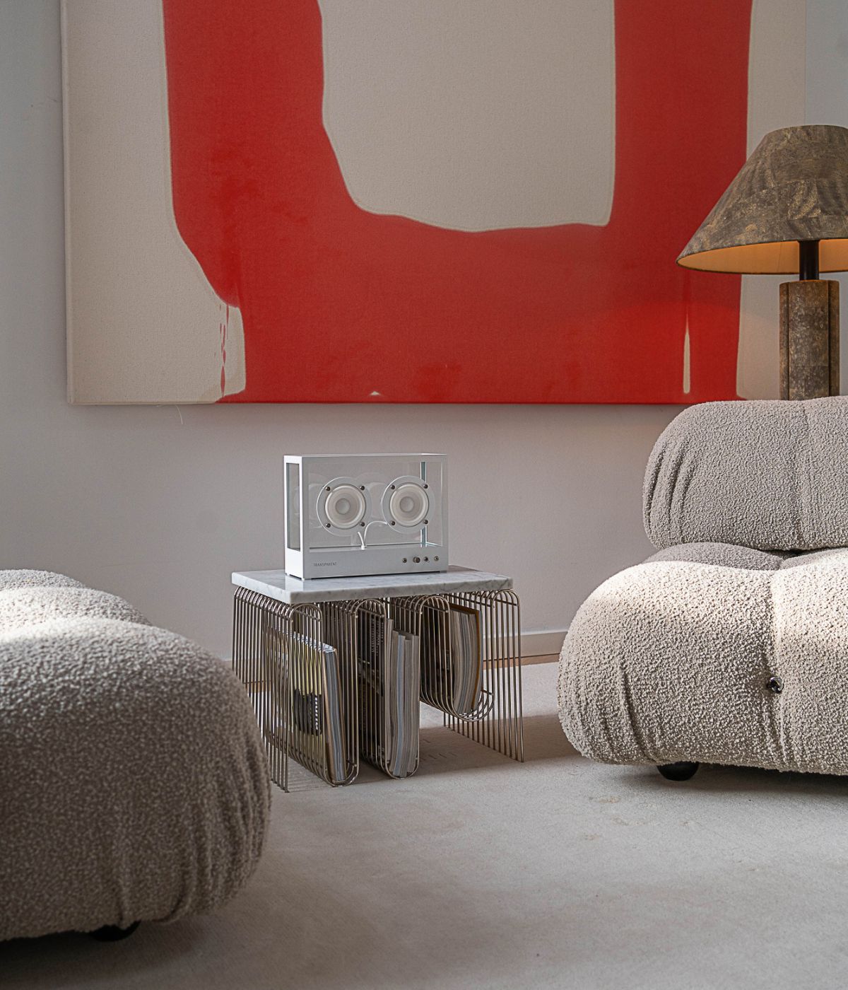 Small Transparent Speaker in Weiß, stilvoll inszeniert in einem modernen Wohnzimmer. Der Lautsprecher steht auf einem dezenten Möbelstück, umgeben von einem Interieur mit klaren Linien, neutralen Farben und hochwertiger Einrichtung. Große Fenster, dezente Dekorationen und sorgfältig ausgewählte Möbelstücke unterstreichen das minimalistische, zeitgemäße Ambiente. Das transparente Design des Speakers fügt sich harmonisch in die moderne Umgebung ein und betont seinen Anspruch als technisches wie ästhetisches.